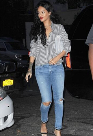Rihanna用寬松的boyfriend style條紋襯衫搭配破洞牛仔褲街頭感十足，細帶涼鞋與紅唇為造型增添女人味。
